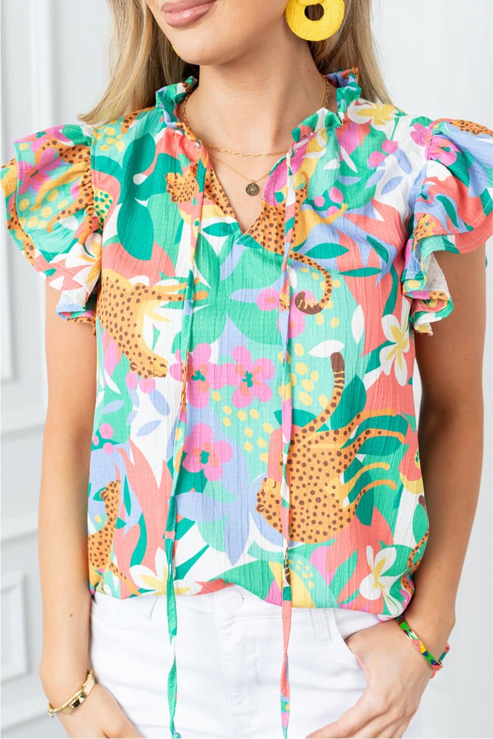 Floral green tie-neck blouse with chic print and ruffled flutter sleeves.