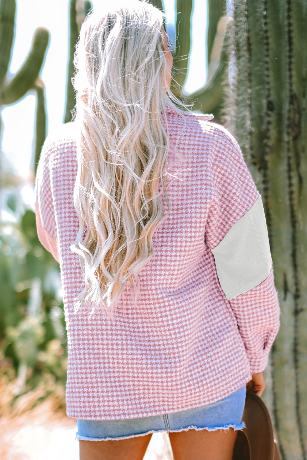 Pink houndstooth color contrast textured patchwork loose shacket worn by a woman outdoors.