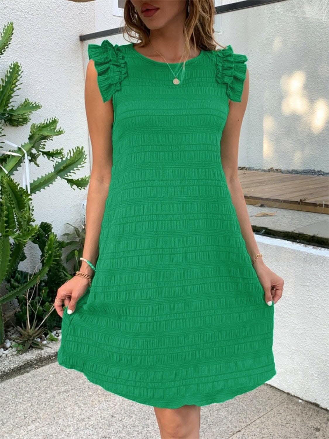 Chic green ruffled sleeveless dress with round neck and elegant design.