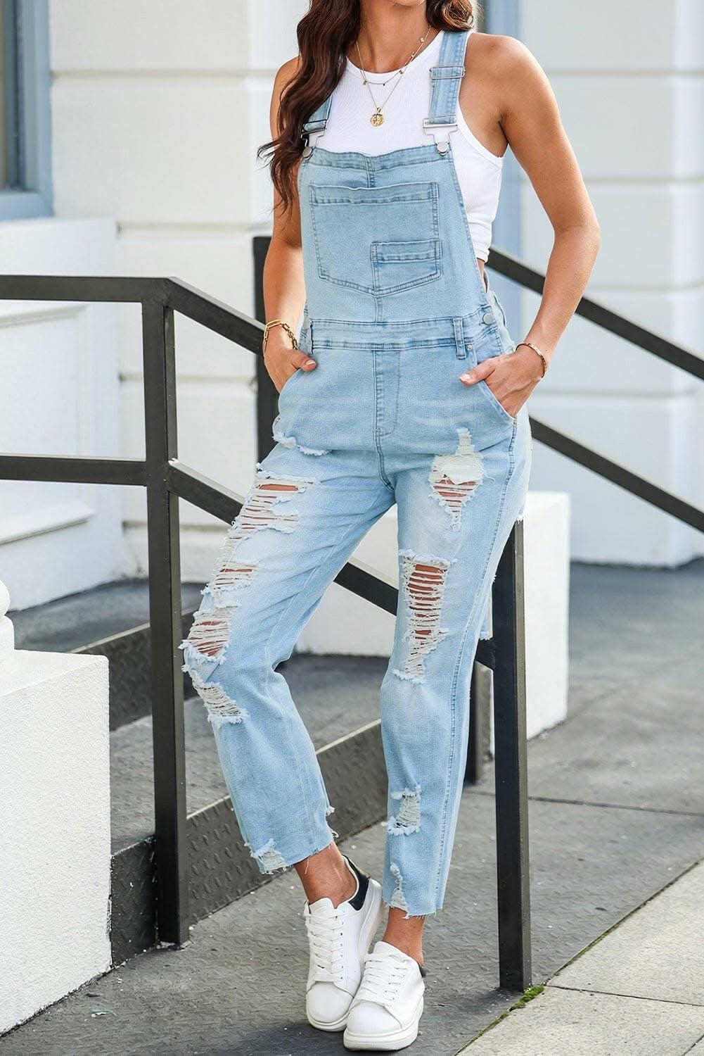 Trendy distressed denim overalls with fashionable worn-in appearance, featuring handy pockets and durable material.