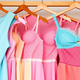 Flying Tomato's plus-size fashion tops and dresses in pastel shades on hangers.