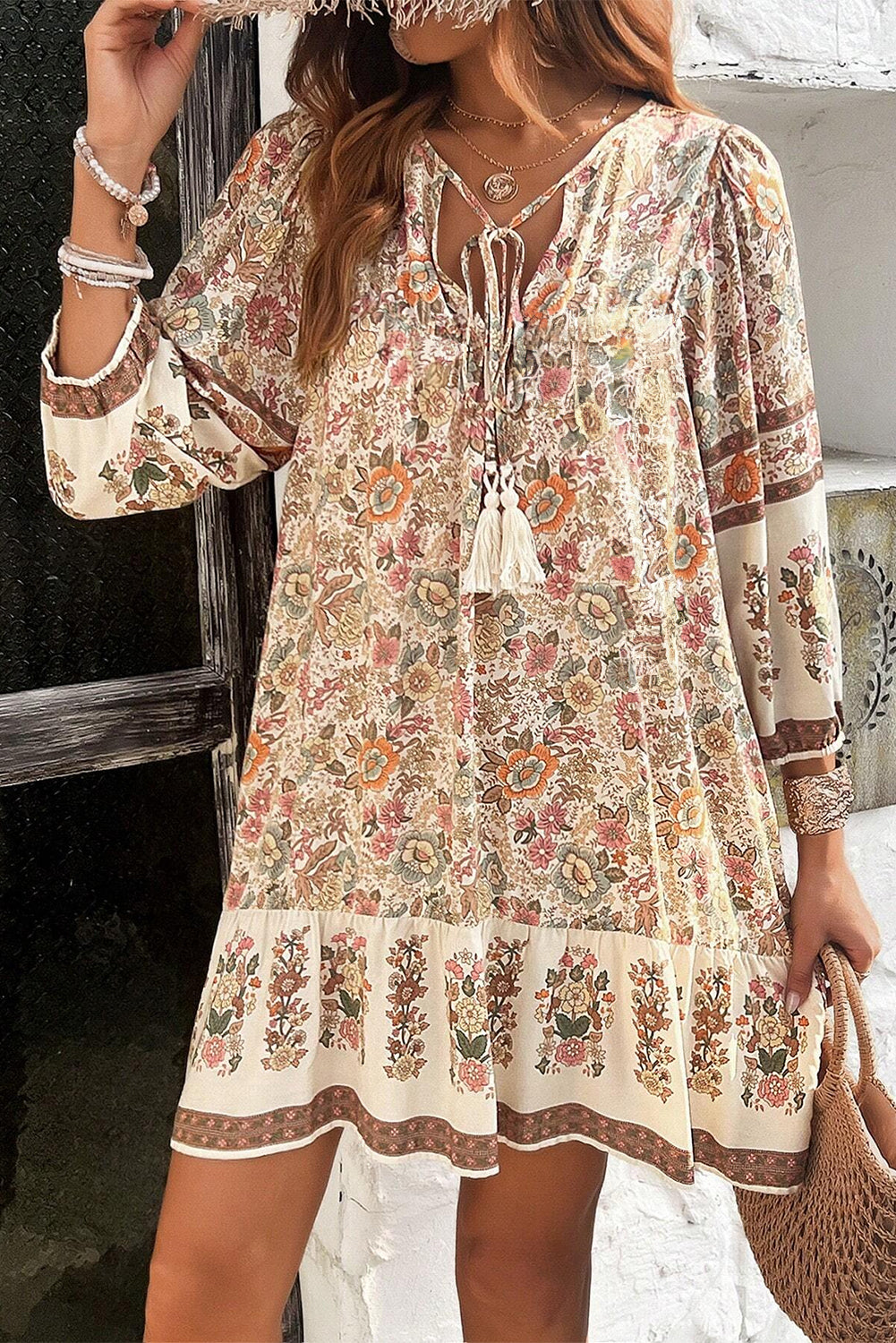 Apricot floral print mini dress with tassel drawstring and V-neckline.