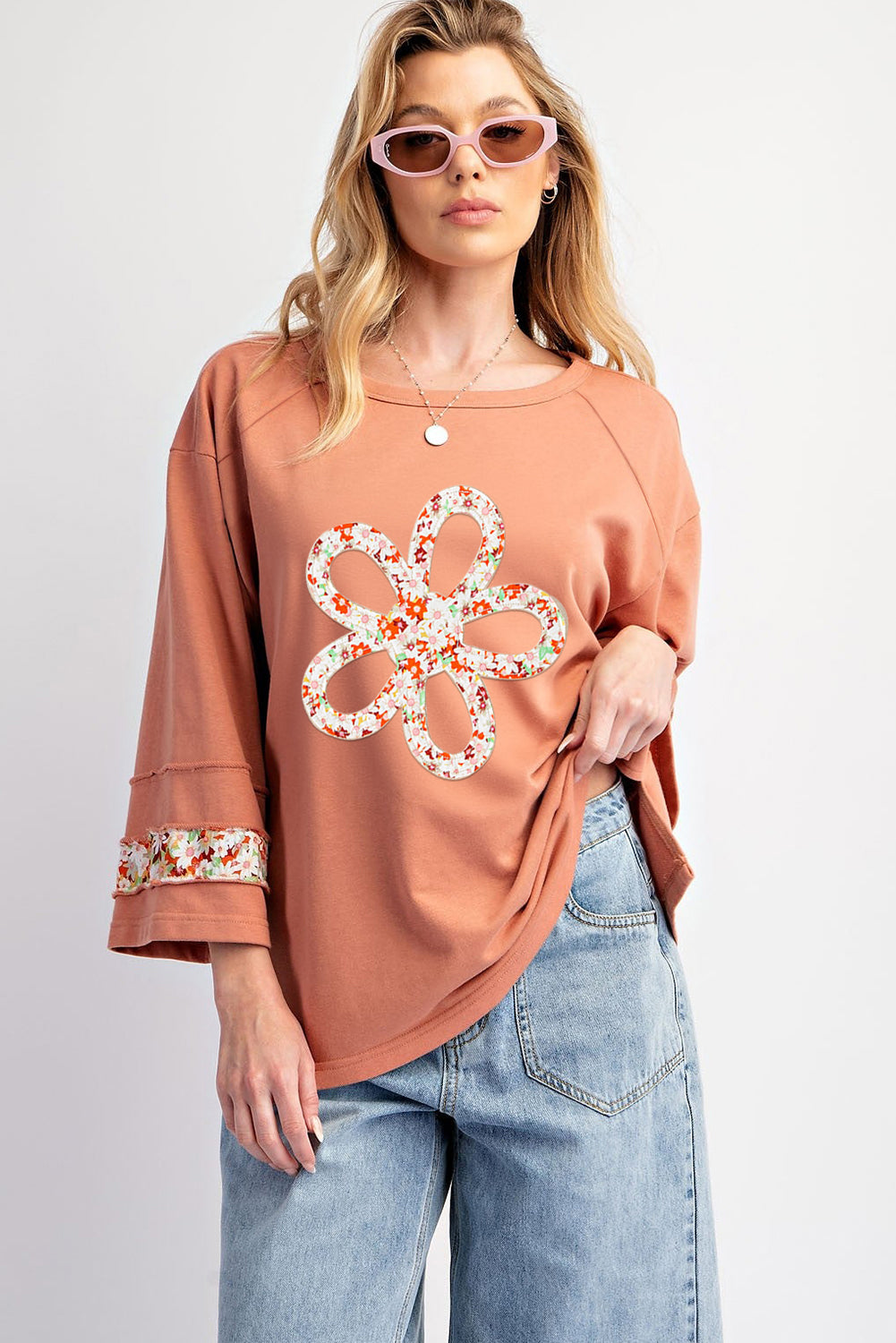 Floral graphic wide-sleeve top with exposed seam detail in grapefruit orange