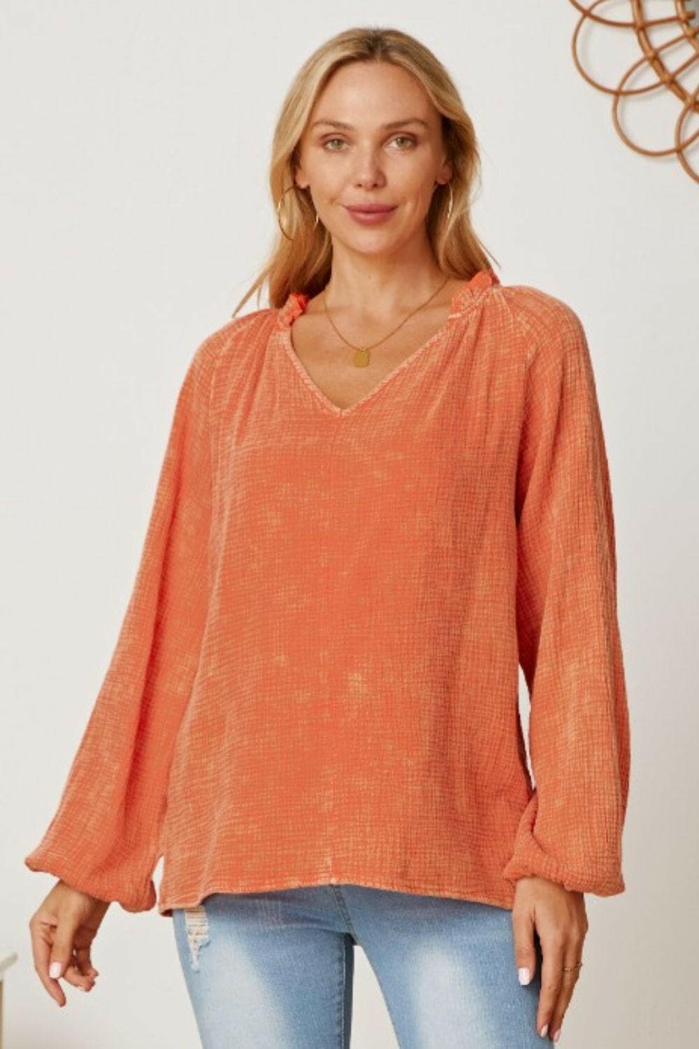 Frill v-neck balloon sleeve blouse in orange with frill accents, modeled.