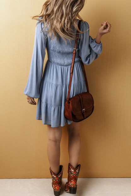 Ashleigh Blue long sleeve smocked tiered mini dress with V-neck and fit and flare silhouette.