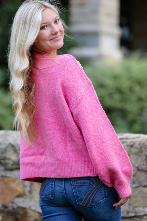 Close-up of pearl bow detail on Miss Sparkling knit sweater. Soft knit texture and delicate pearl accents.