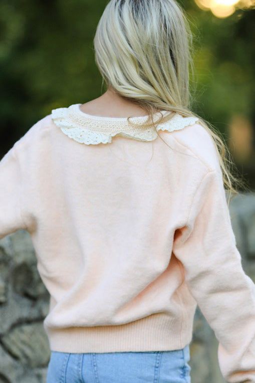 Close-up of the ruffled trim and front tie detail on a Miss Sparkling cardigan. Shows the soft knit texture.