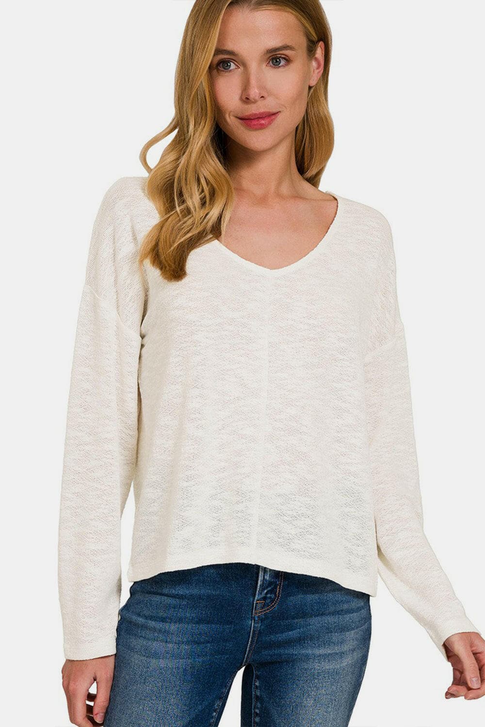 Zenana V-neck dropped shoulder long sleeve tee in white, paired with blue jeans.