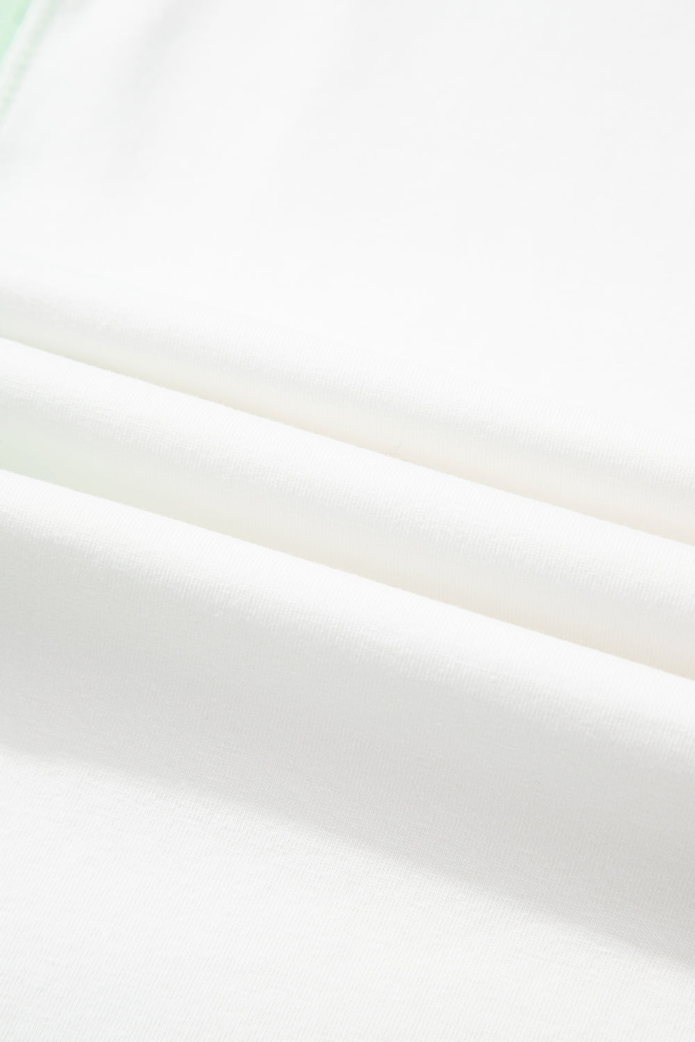 Light green color block t-shirt fabric close-up showing soft texture and exposed seams.