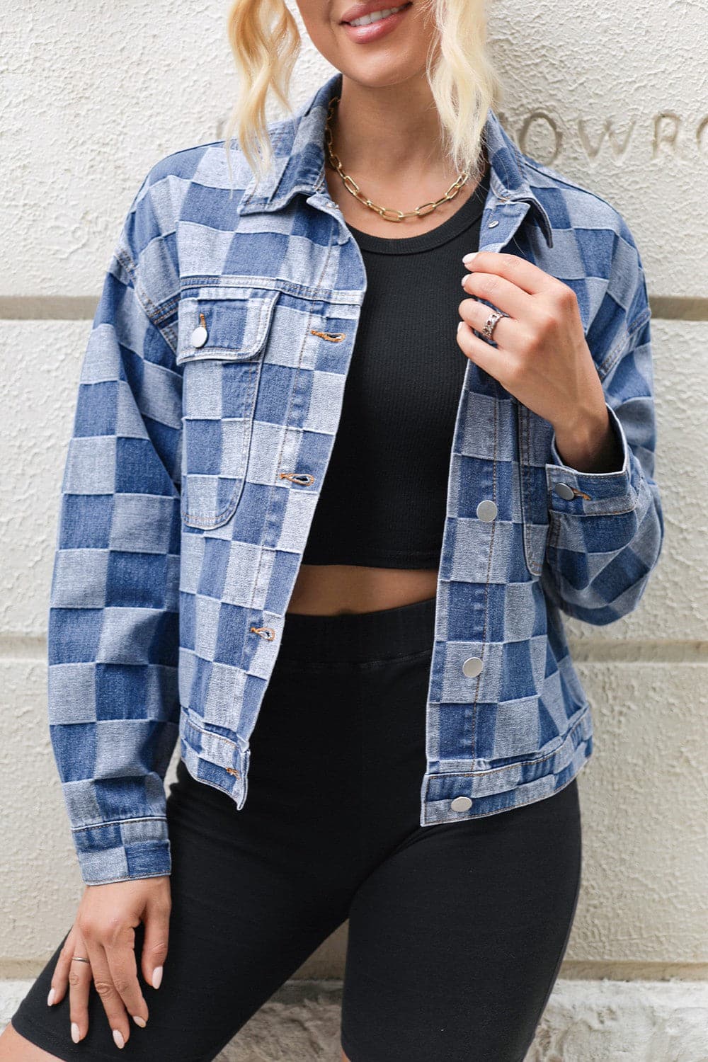 Checkered denim long-sleeve jacket with button closure, modeled over a black top.