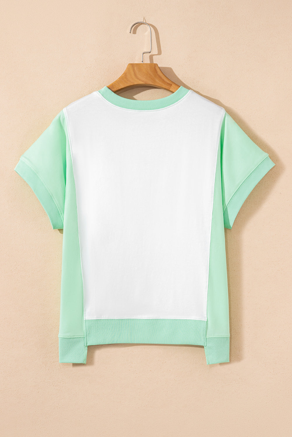 Light green color block crew neck t-shirt with exposed seams and short sleeves on a hanger.