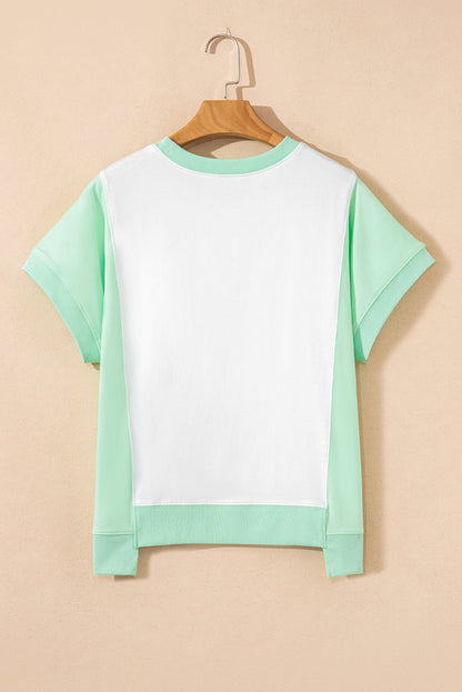 Light green color block crew neck t-shirt with exposed seams and short sleeves on a hanger.