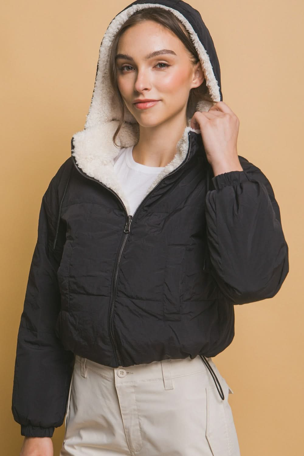 Cropped hooded Sherpa reversible jacket in black with zipper closure, worn by model.