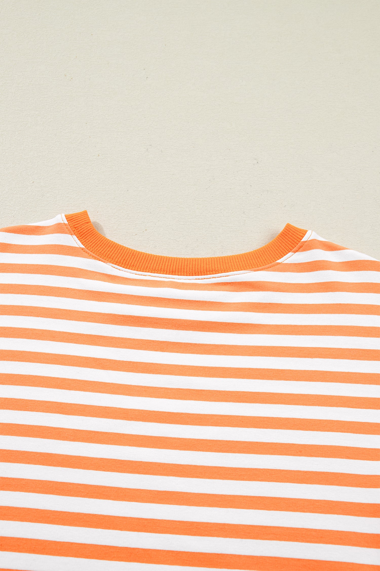 Orange stripe patchwork pullover close-up of exposed seam construction and fabric texture