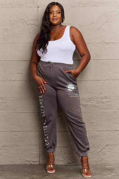 Plus-size model wearing Celestial Dreamer graphic pants with adjustable drawstring waist and whimsical pattern.