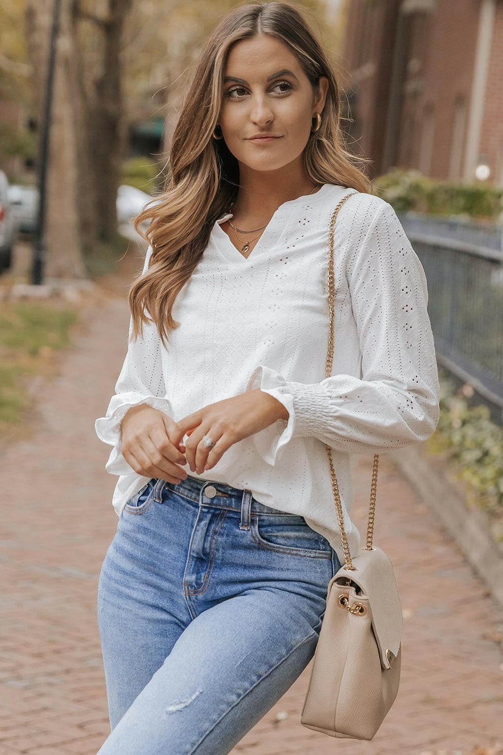 Sheer flounce sleeve blouse with openwork design, worn by a woman with a purse.