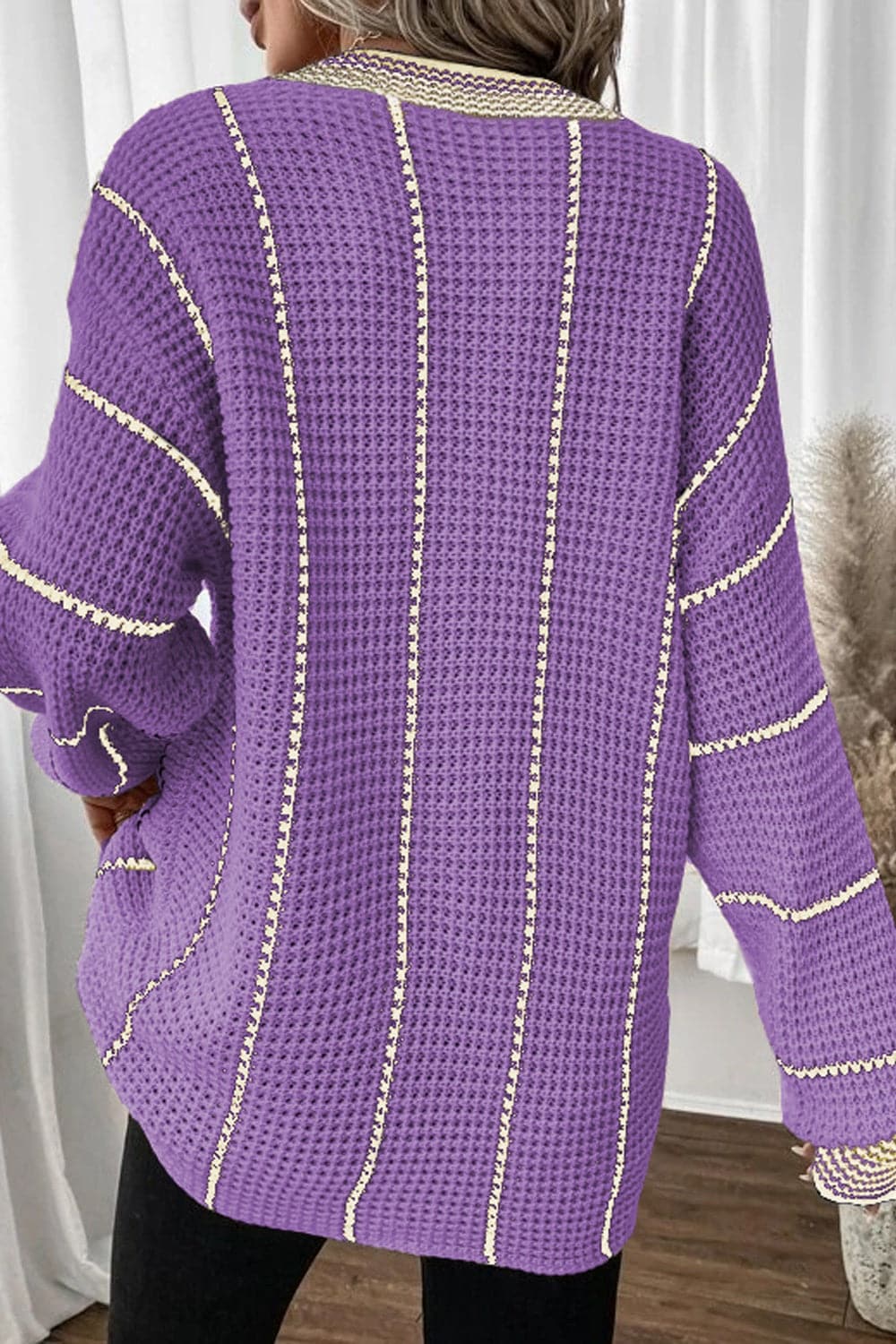 Vibrant striped v-neck sweater in purple with long sleeves, slightly stretchy acrylic material.