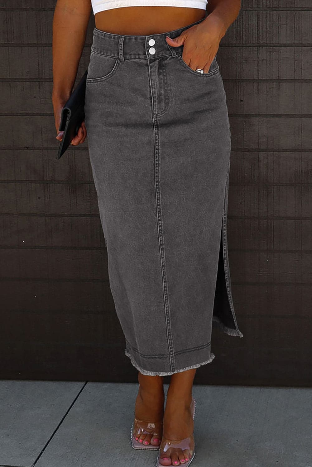 Edgy denim midi skirt with slit, raw hem, and pockets.