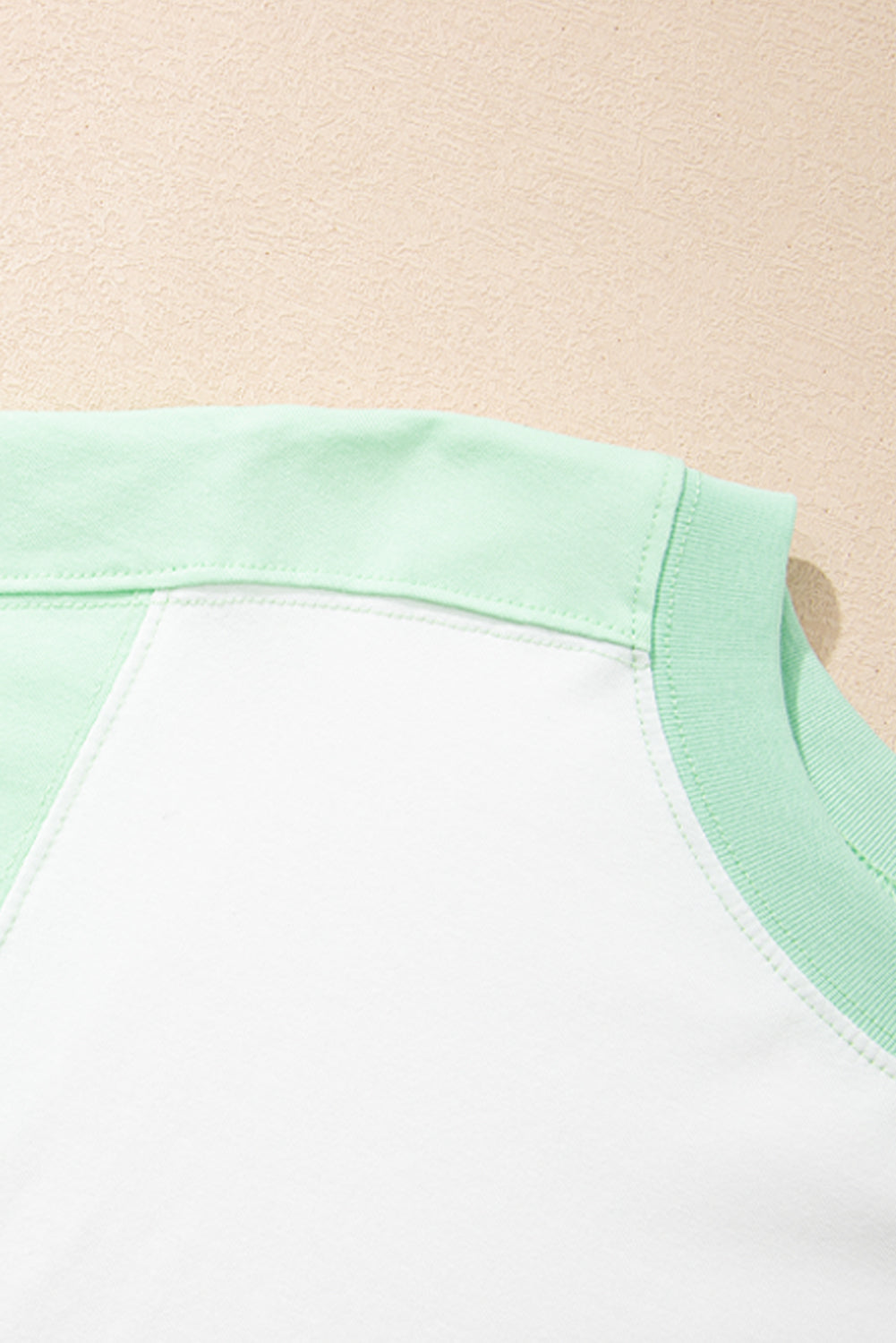 Light green color block exposed seam crew neck T-shirt detail.