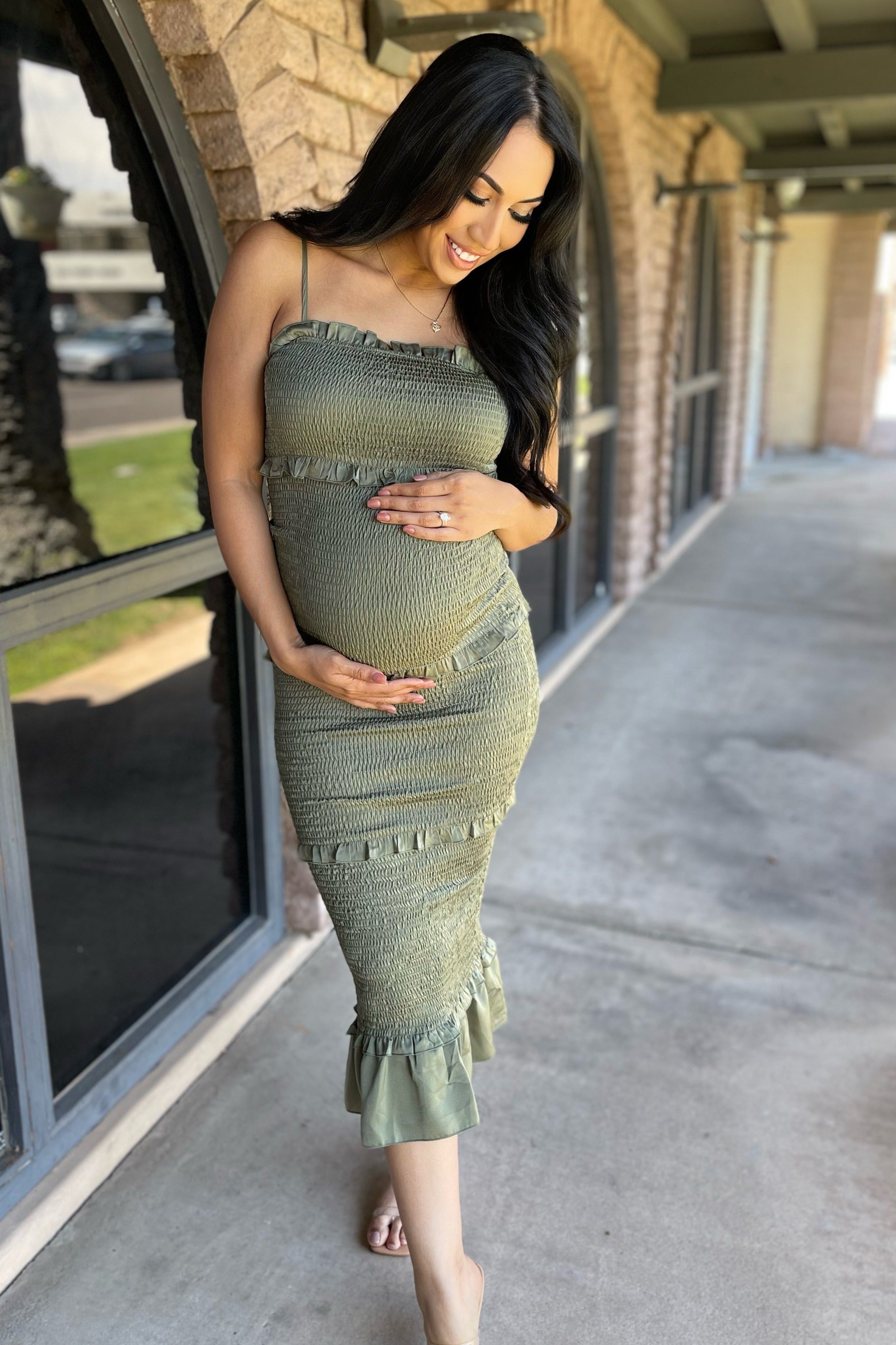 PinkBlush Olive Satin Smocked Fitted Maternity Midi Dress, shown in a lifestyle setting, emphasizing its comfortable fit.