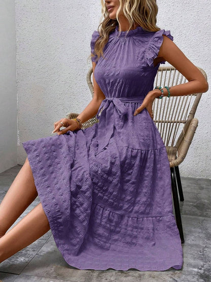 Purple ruffled cap sleeve midi dress with tie waist, sitting on chair.