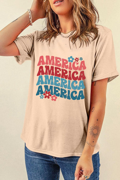 America classic round neck tee with colorful graphic design, short sleeves, beige color, worn by a woman with jeans.