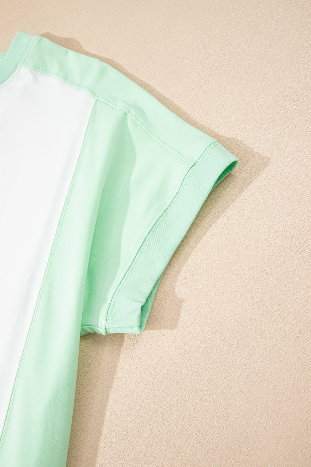 Light green color block exposed seam crew neck t-shirt with short sleeves.