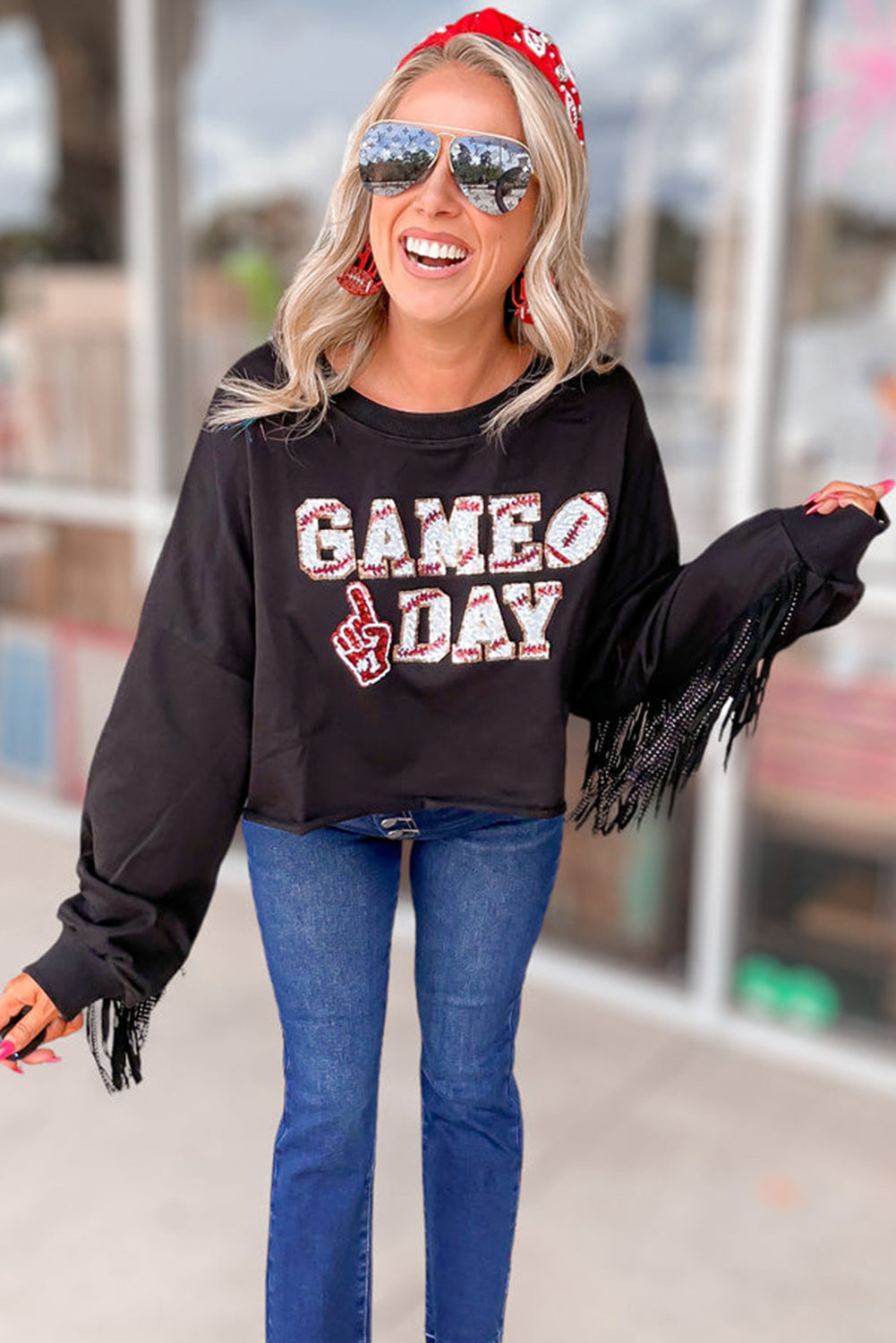 Sparkle on game day with a black cropped rugby sweatshirt featuring tassels and sequins