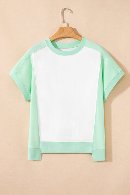 Light green color block exposed seam crew neck t-shirt hanging on a wooden hanger.