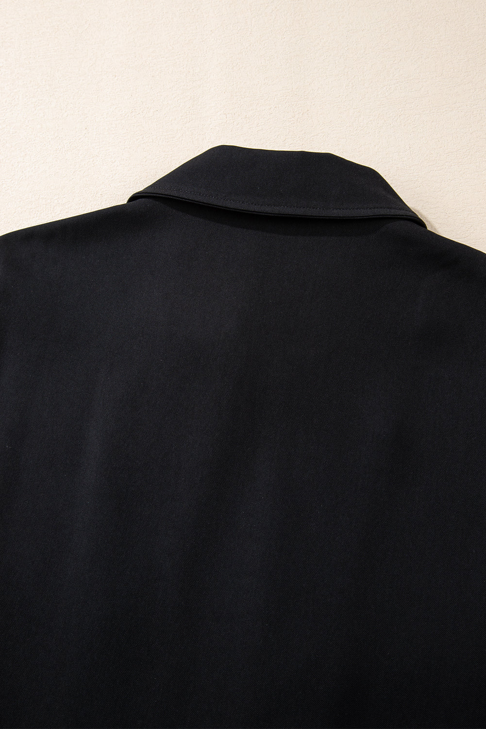 Sleek black zip-up jacket with tab sleeves and flap details