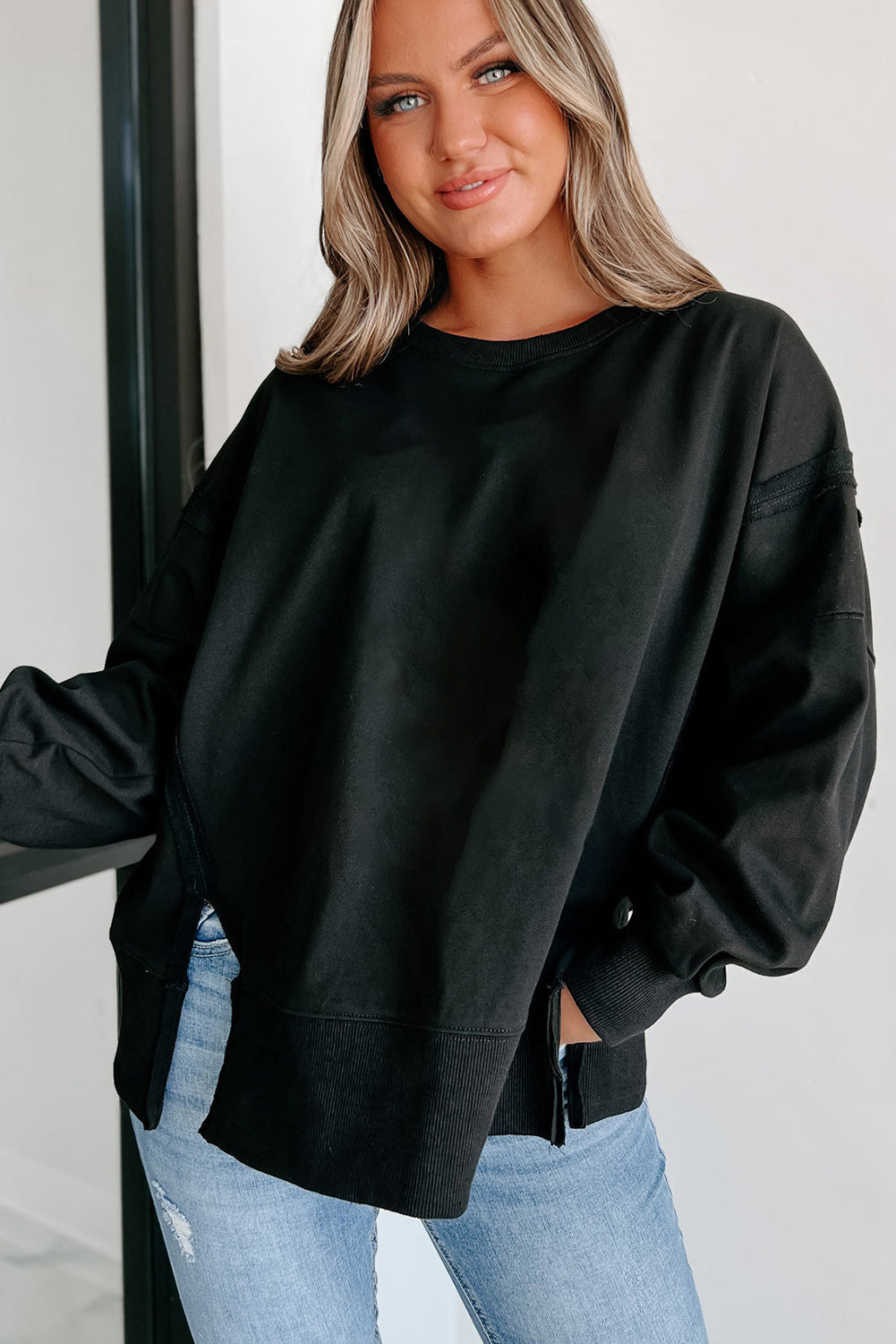 Chic black drop shoulder sweatshirt with exposed seams and side slits