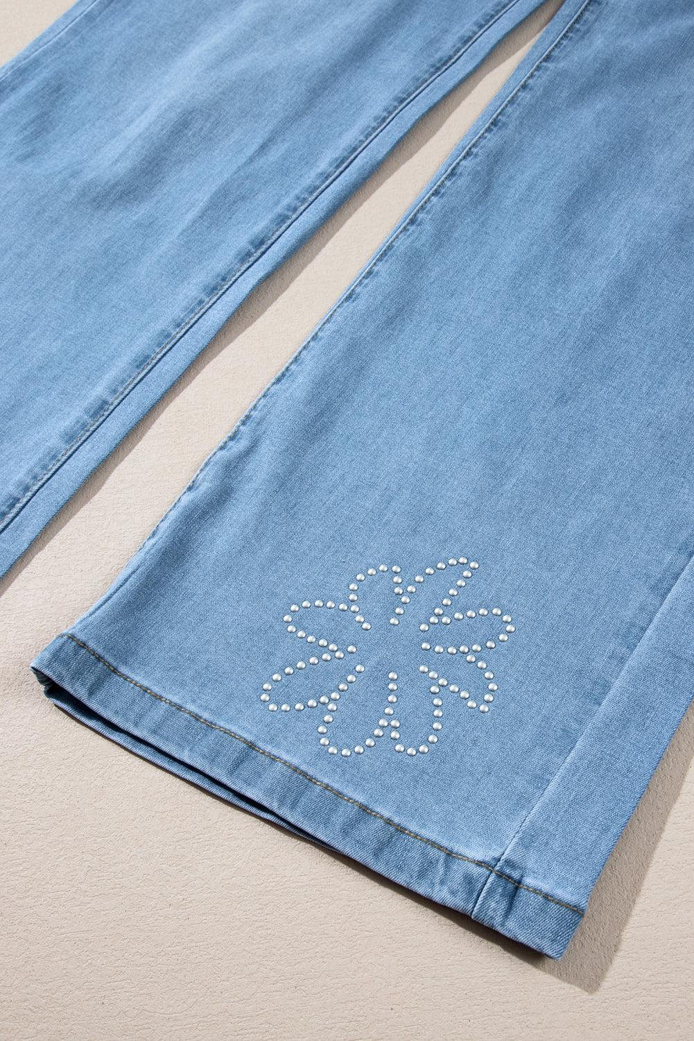 Light blue high-rise wide leg jeans with floral rhinestone embellishments