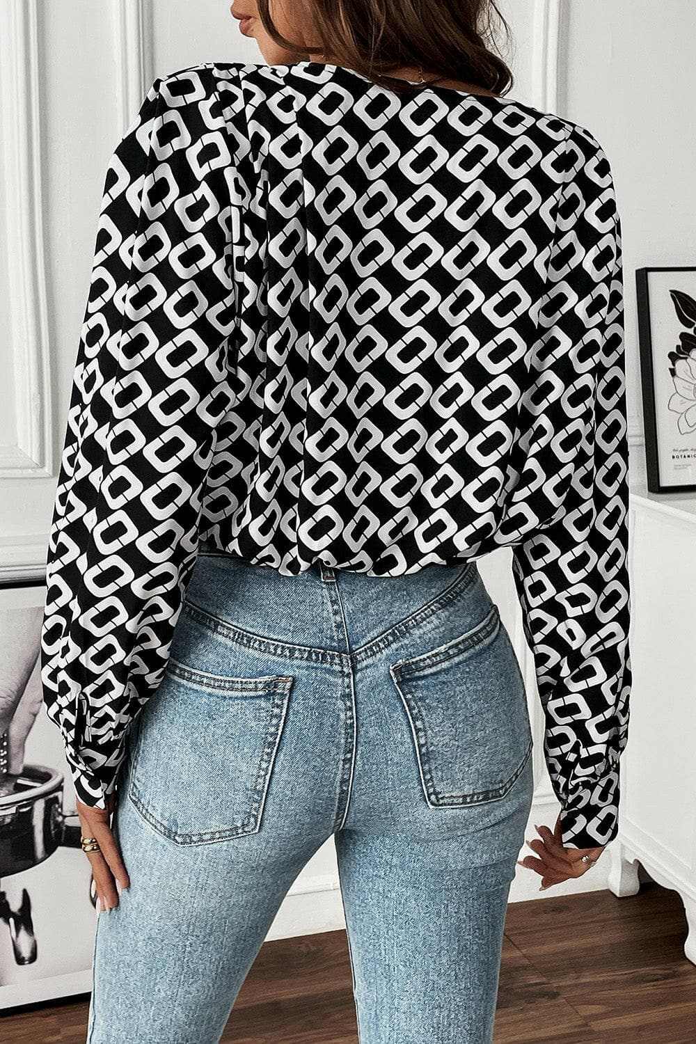 Geometric v-neck long sleeve blouse with black and white pattern, paired with blue jeans.