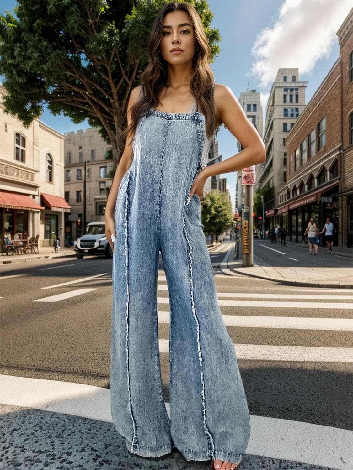 Wide leg denim overalls with adjustable straps, worn by a woman standing on a city street.