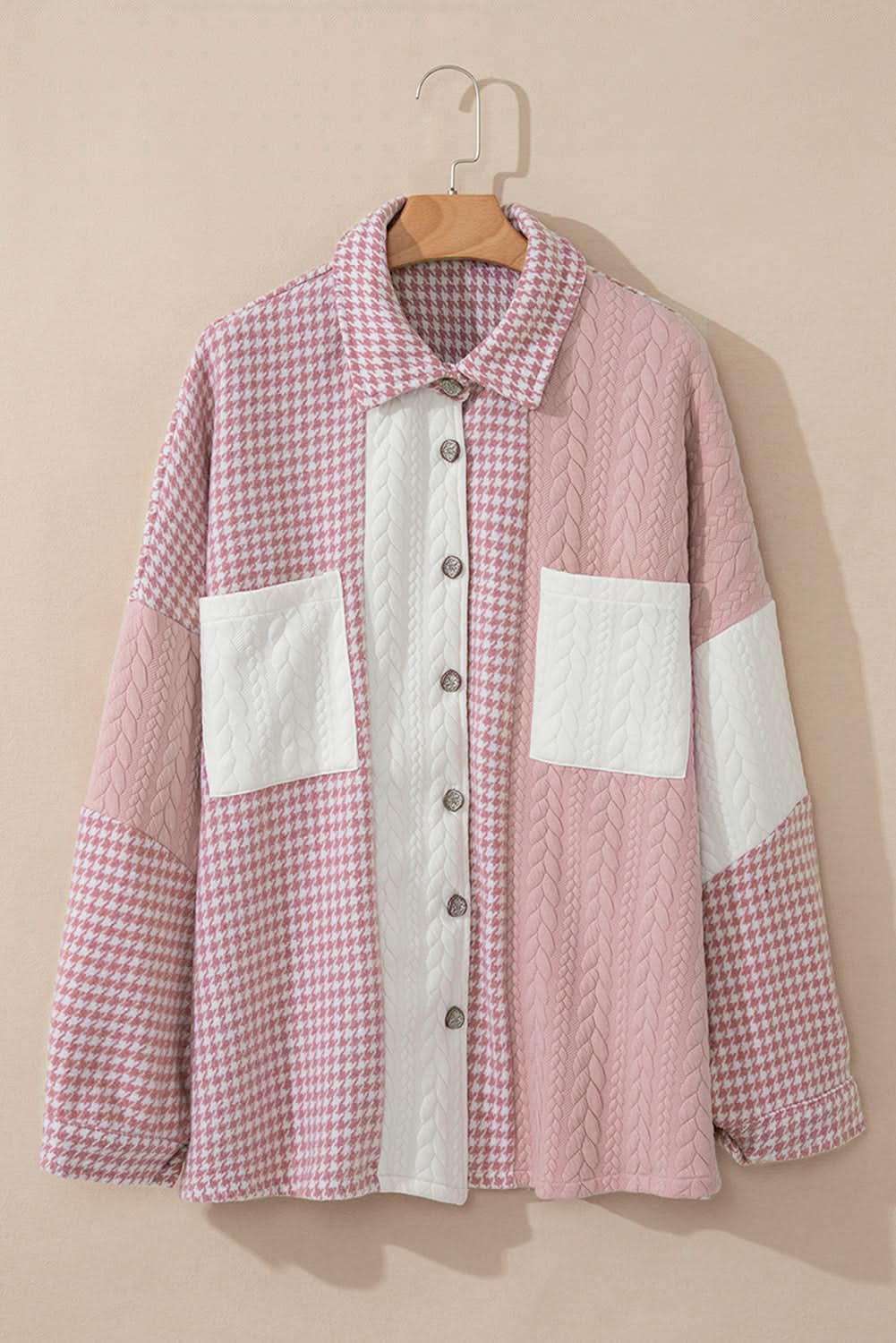 Pink houndstooth color contrast textured patchwork loose shacket hanging on a hanger.