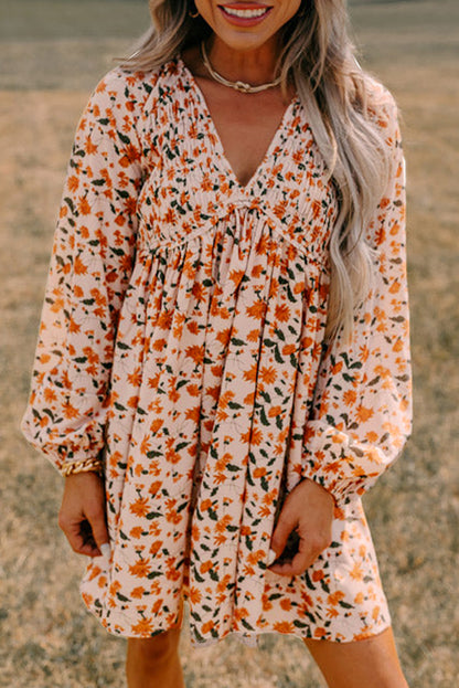 Beige floral deep V-neck babydoll dress with smocked bust and bubble sleeves.