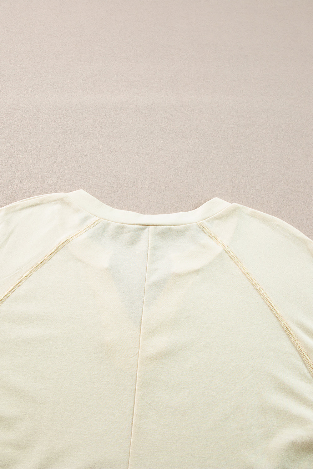 Chic apricot long sleeve top with notched neckline and exposed stitching