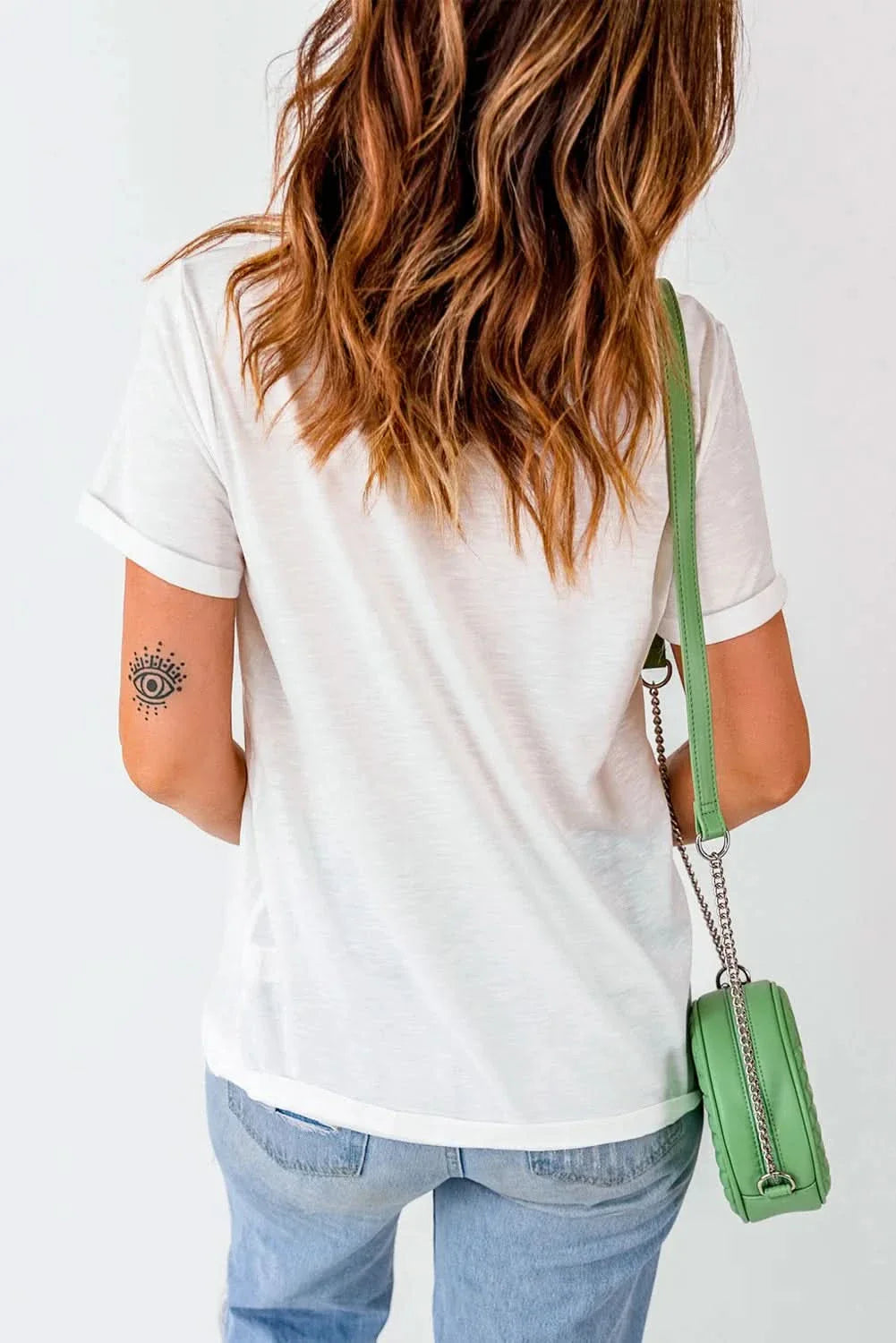 Woman wearing a MERRY Round Neck Short Sleeve T-Shirt in white, paired with jeans and a green purse.