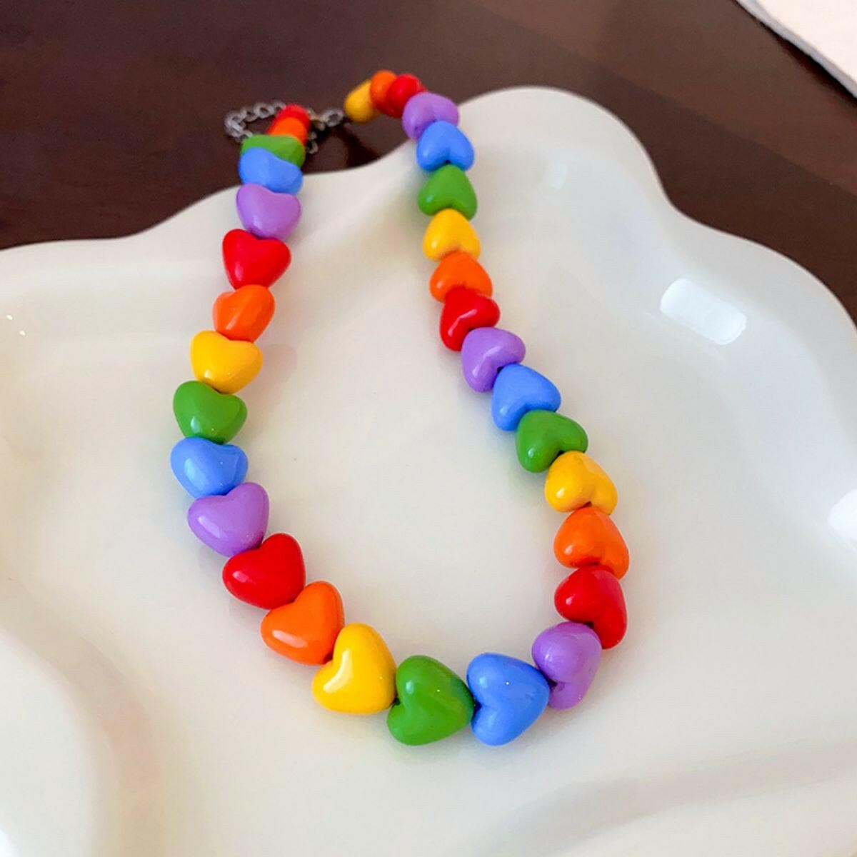 Colorful alloy heart pendant necklace with heart-shaped beads on a plate.