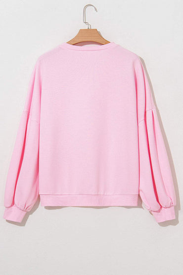 Light pink oversized pullover sweatshirt with lantern sleeves and embroidered bow details.