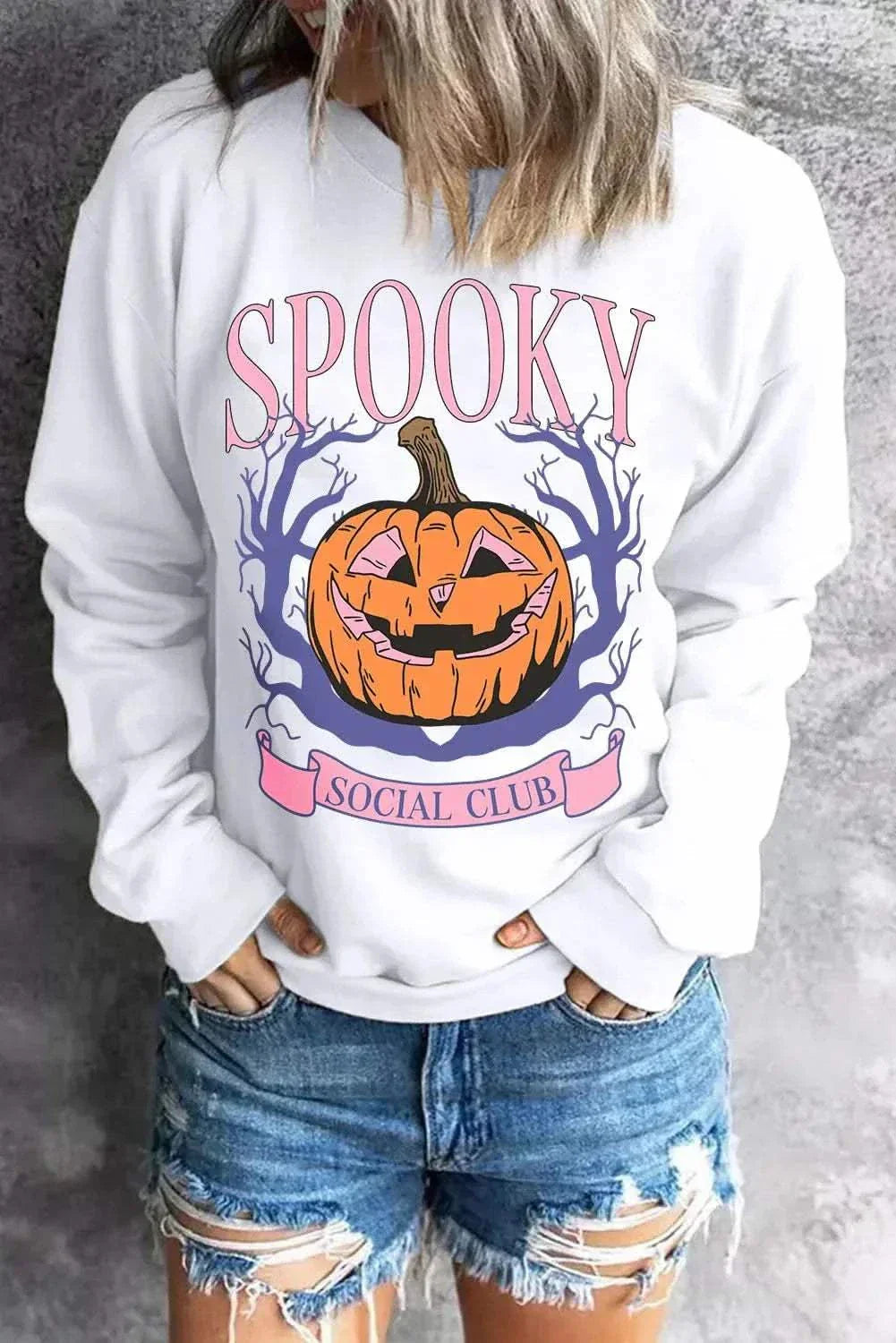 Jack-O'-Lantern Round Neck Long Sleeve Sweatshirt with spooky pumpkin design, worn with denim shorts.