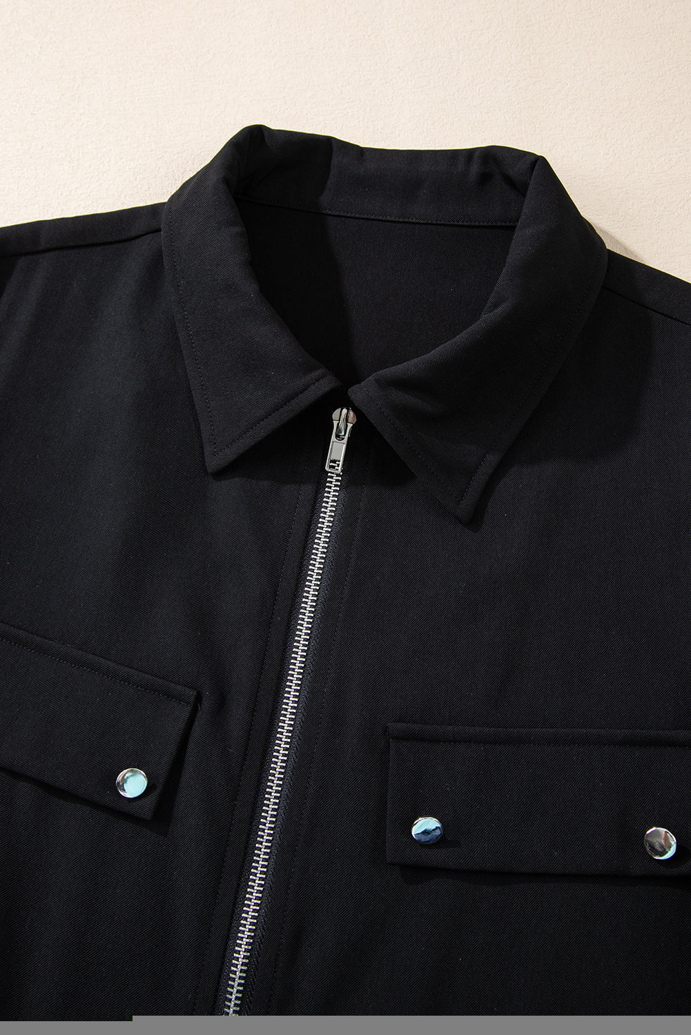 Sleek black zip-up jacket with tab sleeves and flap details