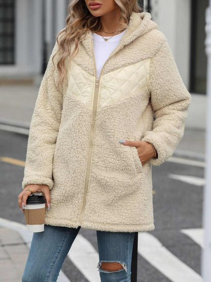 Cozy fleece hooded jacket with pockets in beige, worn by woman holding coffee.