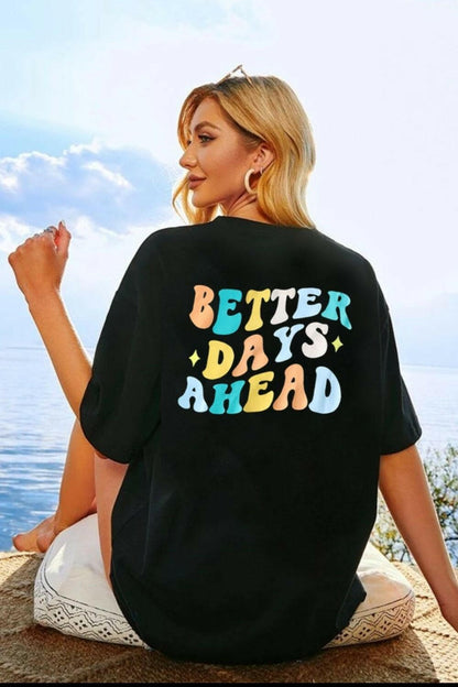 Brighter Days Ahead Round Neck Tee with colorful graphic text on the back, worn by a woman sitting outdoors.