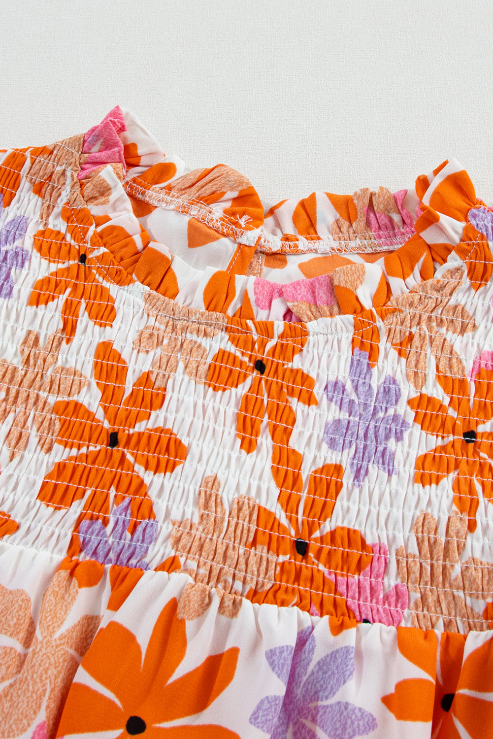 Floral delight: Orange ruffled sleeve top with smocked detail