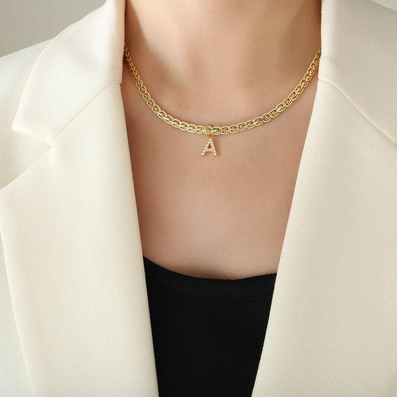 Brass inlaid zircon letter pendant necklace on a person wearing a white blazer.