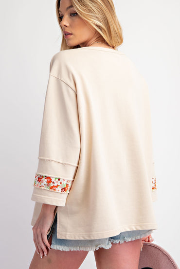 Beige floral graphic wide sleeve top with exposed seams