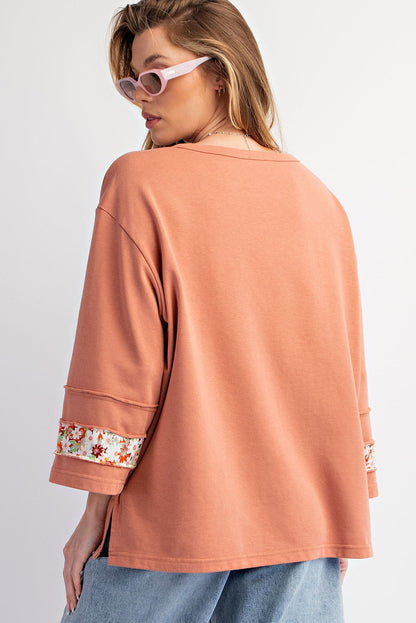 Floral graphic wide-sleeve top with exposed seam detail in grapefruit orange