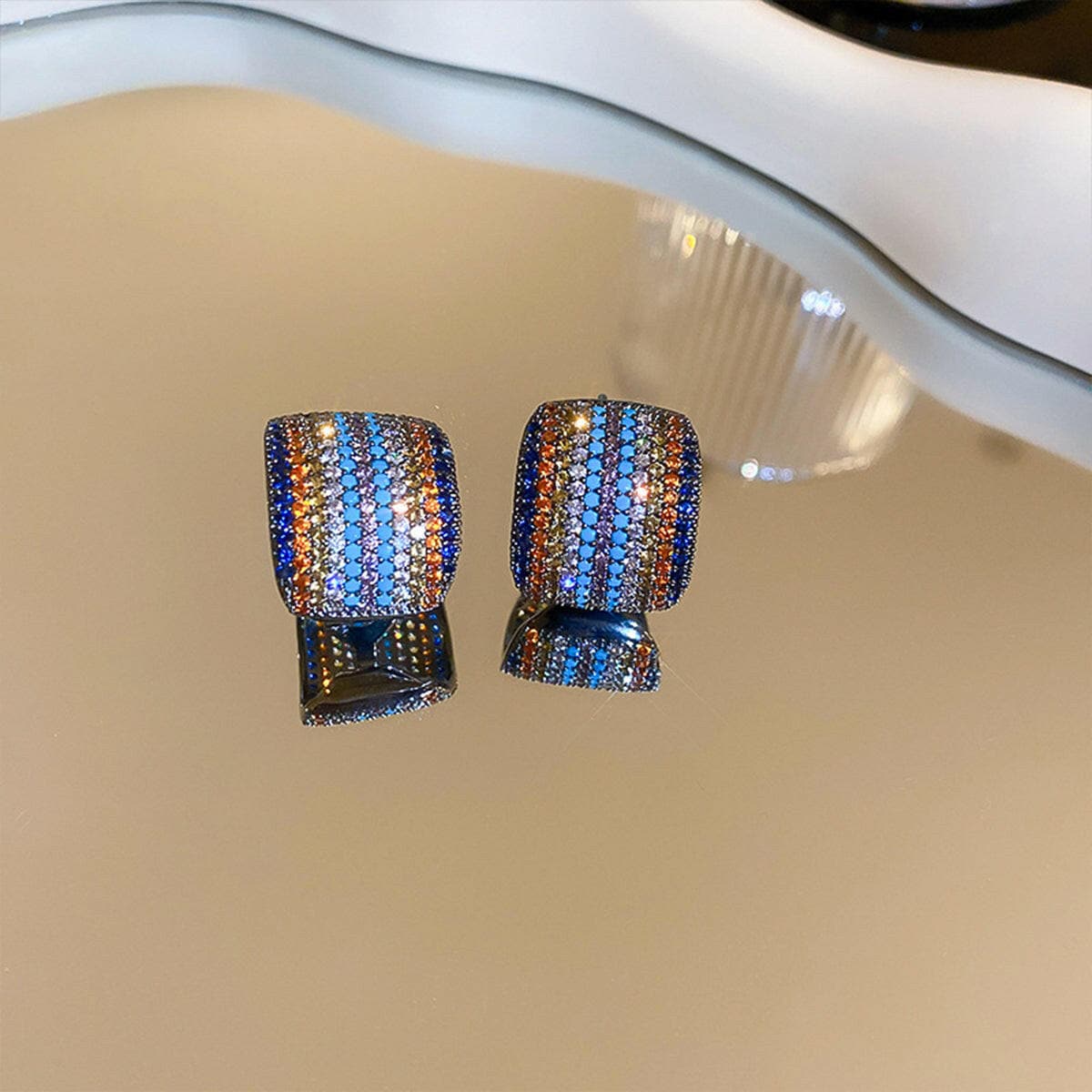 Contrast inlaid zircon earrings with elegant zircon inlay on copper, reflecting light on a surface.