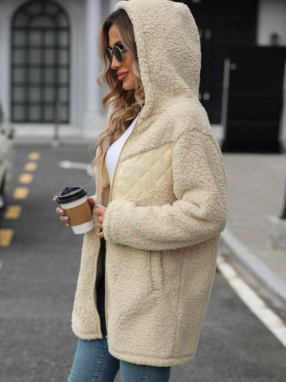 Woman wearing cozy fleece hooded jacket with pockets.